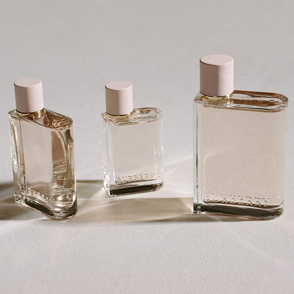 Drei Burberry Her Flakons. Rechteckige Form, rosa Flüssigkeit, rosa Verschluss. Unterschiedliche Größen.