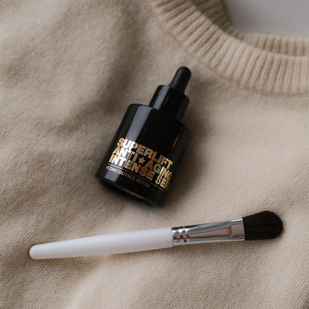 Schwarze Flasche mit goldfarbenem Text: Superlift Anti-Aging Intense Serum. Daneben ein Pinsel.