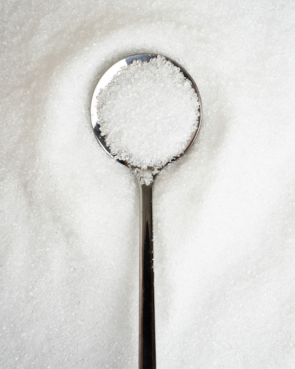 Ein Löffel mit Erythritol, umgeben von Erythritol-Kristallen.