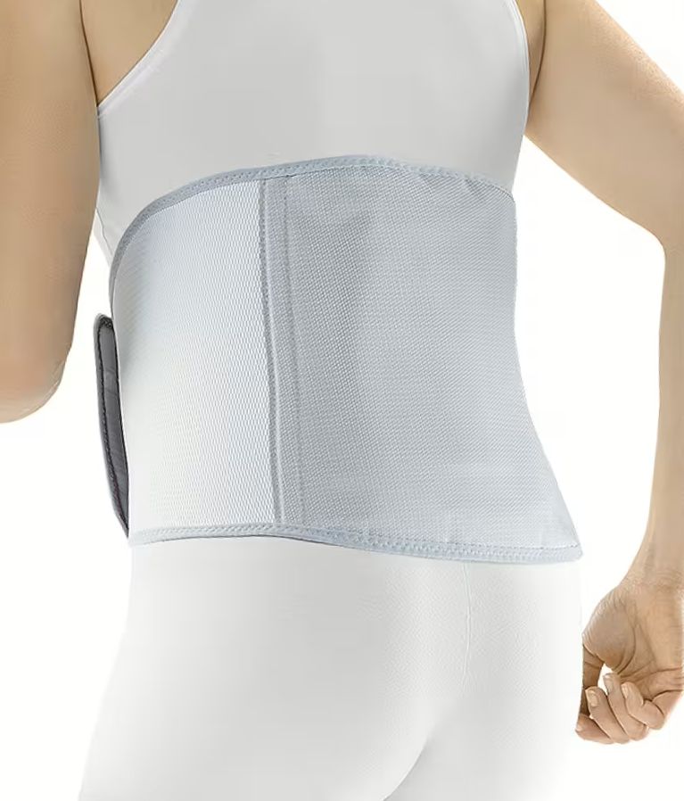 Person trägt eine graue OFA Push care Lumbalbandage. Die Bandage bedeckt den unteren Rücken. Graue Klettverschlüsse.