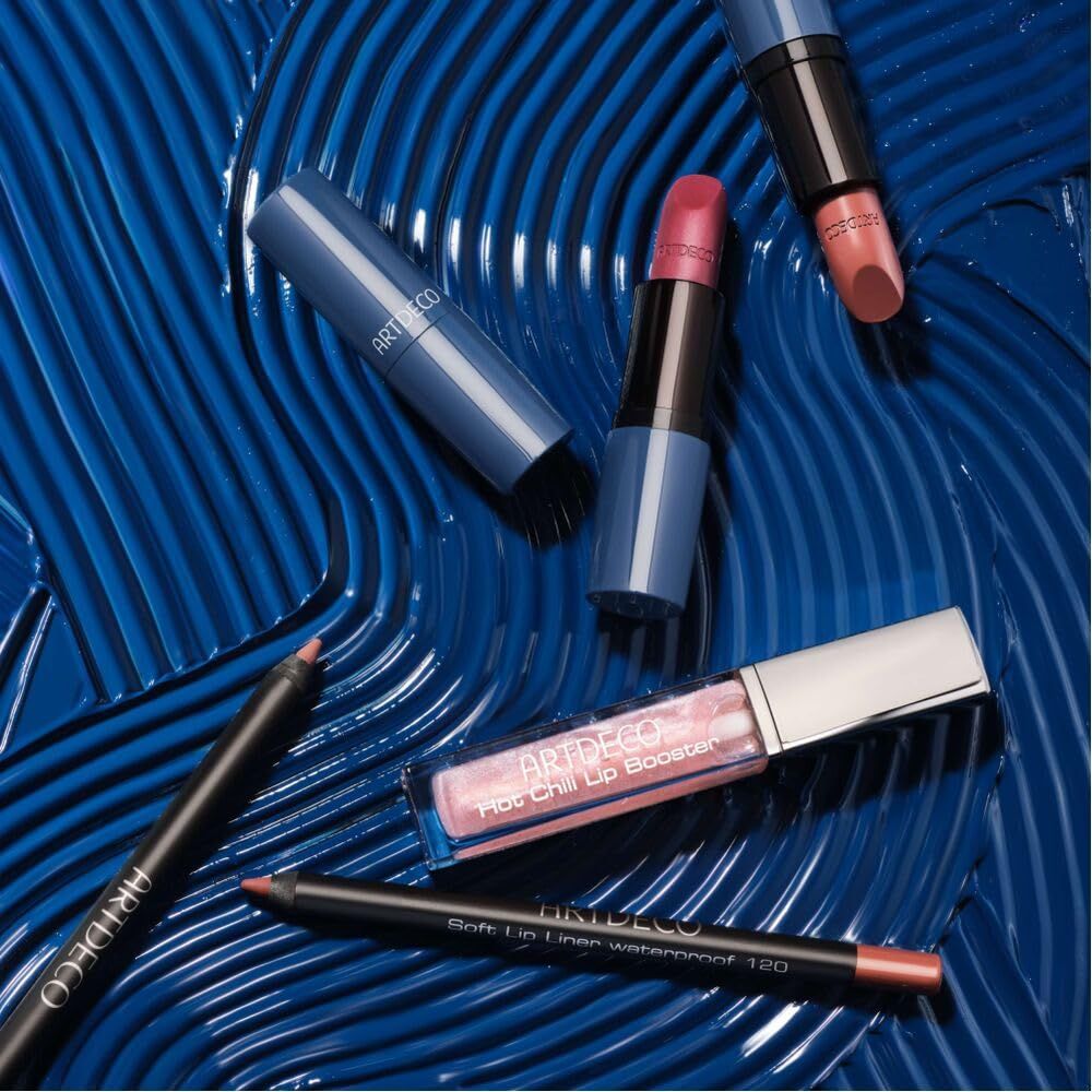 Kosmetikprodukte auf blauem Hintergrund. Artdeco Hot Chili Lip Booster, Lippenstifte, Lipliner. Produktbeschriftung sichtbar.
