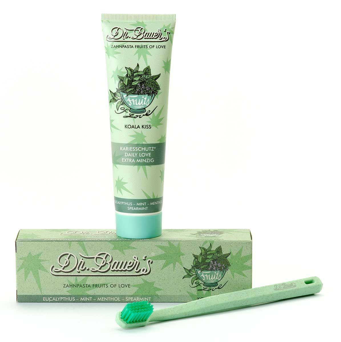 Zahnpasta-Tube, Zahnbürste und Schachtel. Tube und Schachtel mit "Dr. Bauer's Zahnpasta Fruits of Love Koala Kiss". Grüne Zahnbürste.