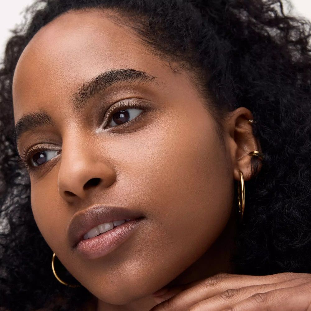 Nahaufnahme eines Gesichts. Kajalstift am unteren Augenlid. Person mit goldenen Ohrringen.