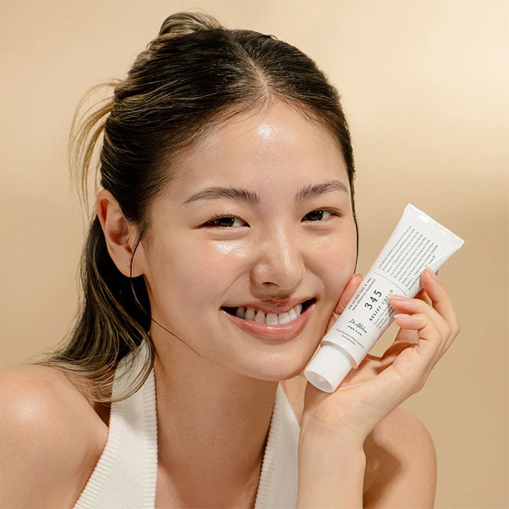 Eine junge Frau hält eine weiße Tube Dr. Althea 345 Relief Cream.