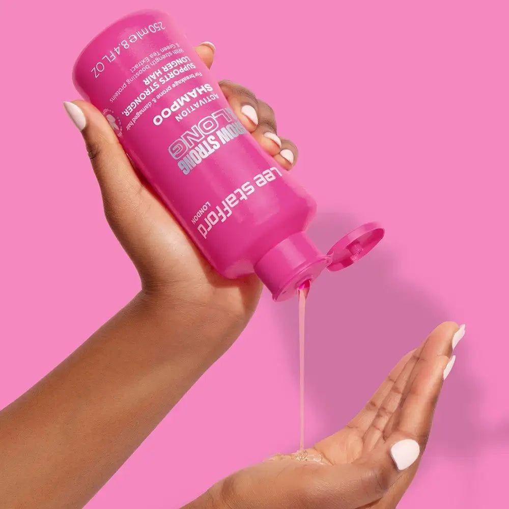 Hand schüttet Lee Stafford Grow Strong & Long Aktivierungs-Shampoo aus einer pinken Flasche in die Handfläche.
