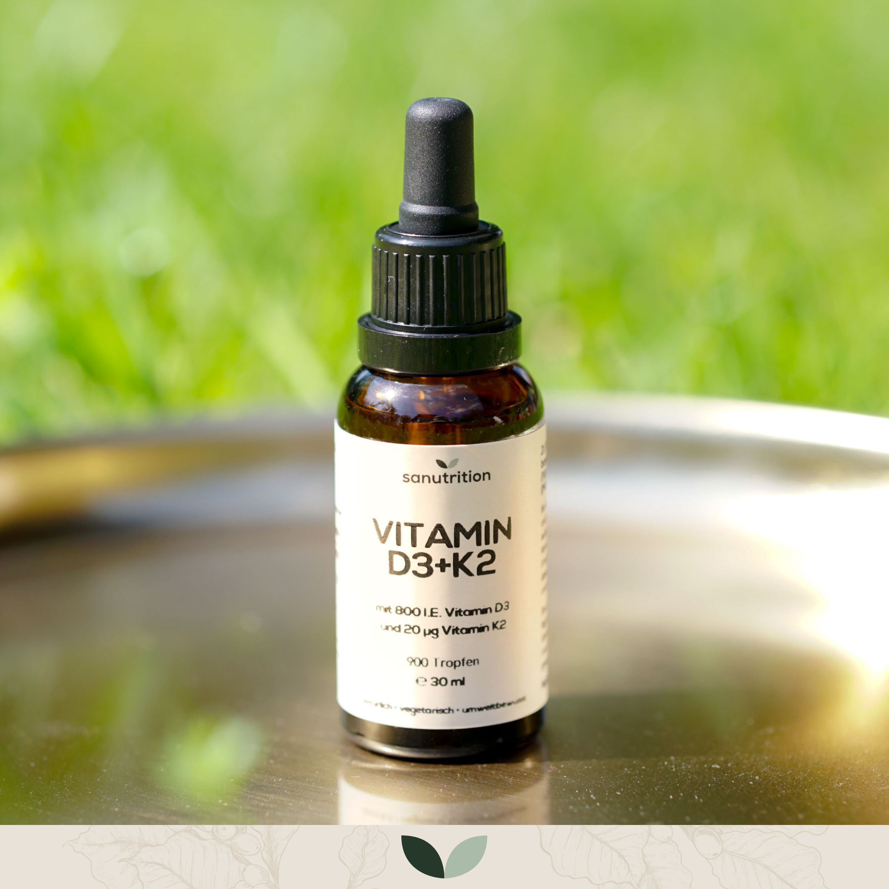 Braune Glasflasche mit schwarzem Tropfer. Etikett mit "Vitamin D3+K2" und "Sanutrition".