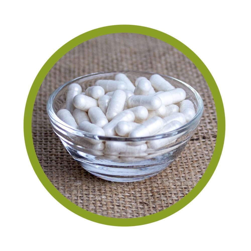 Klare Glasschale gefüllt mit weißen Kapseln. Die Kapseln haben eine längliche Form.
