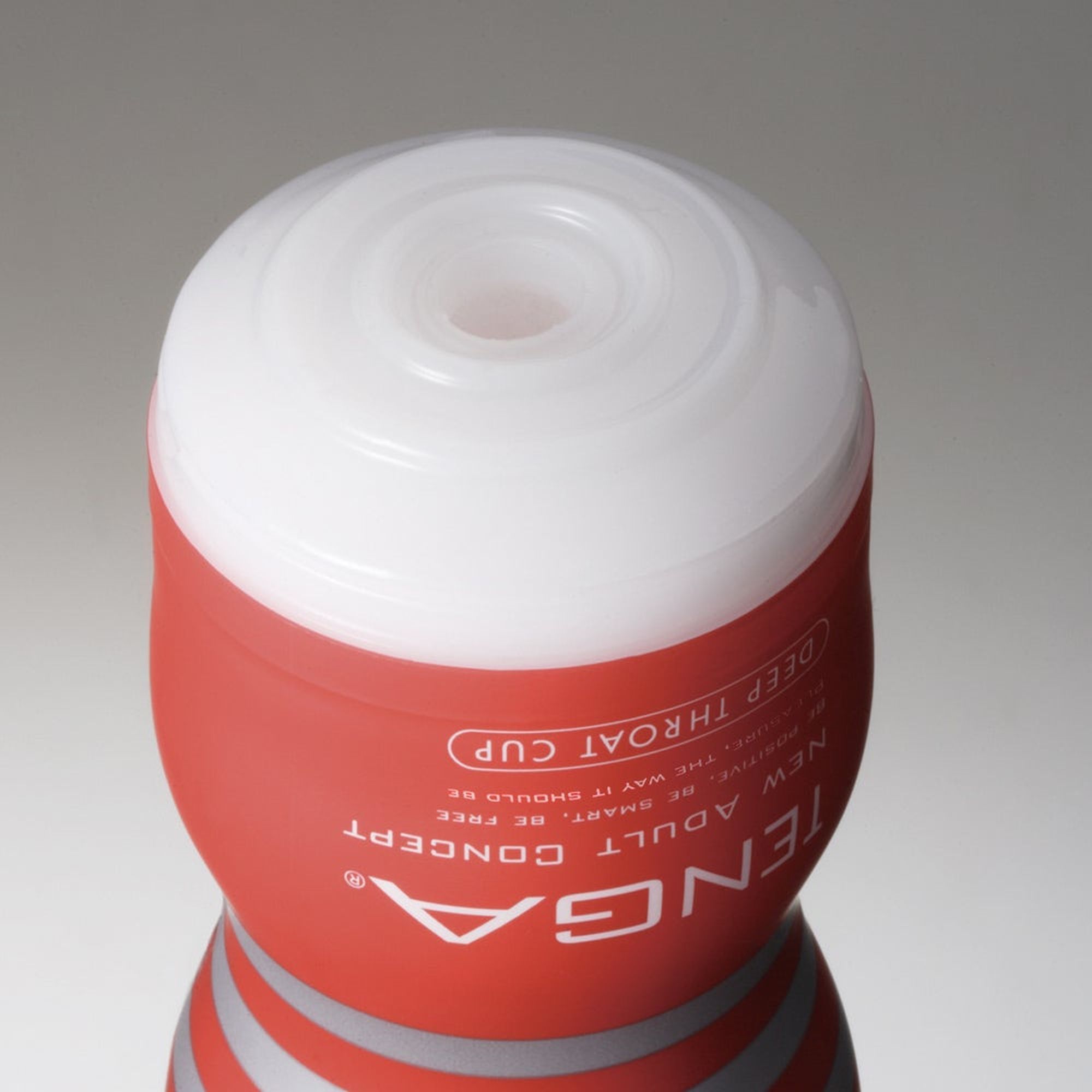 Roter Masturbator mit weißem Deckel. Text: TENGA, DEEP THROAT CUP. Silberne Streifen.