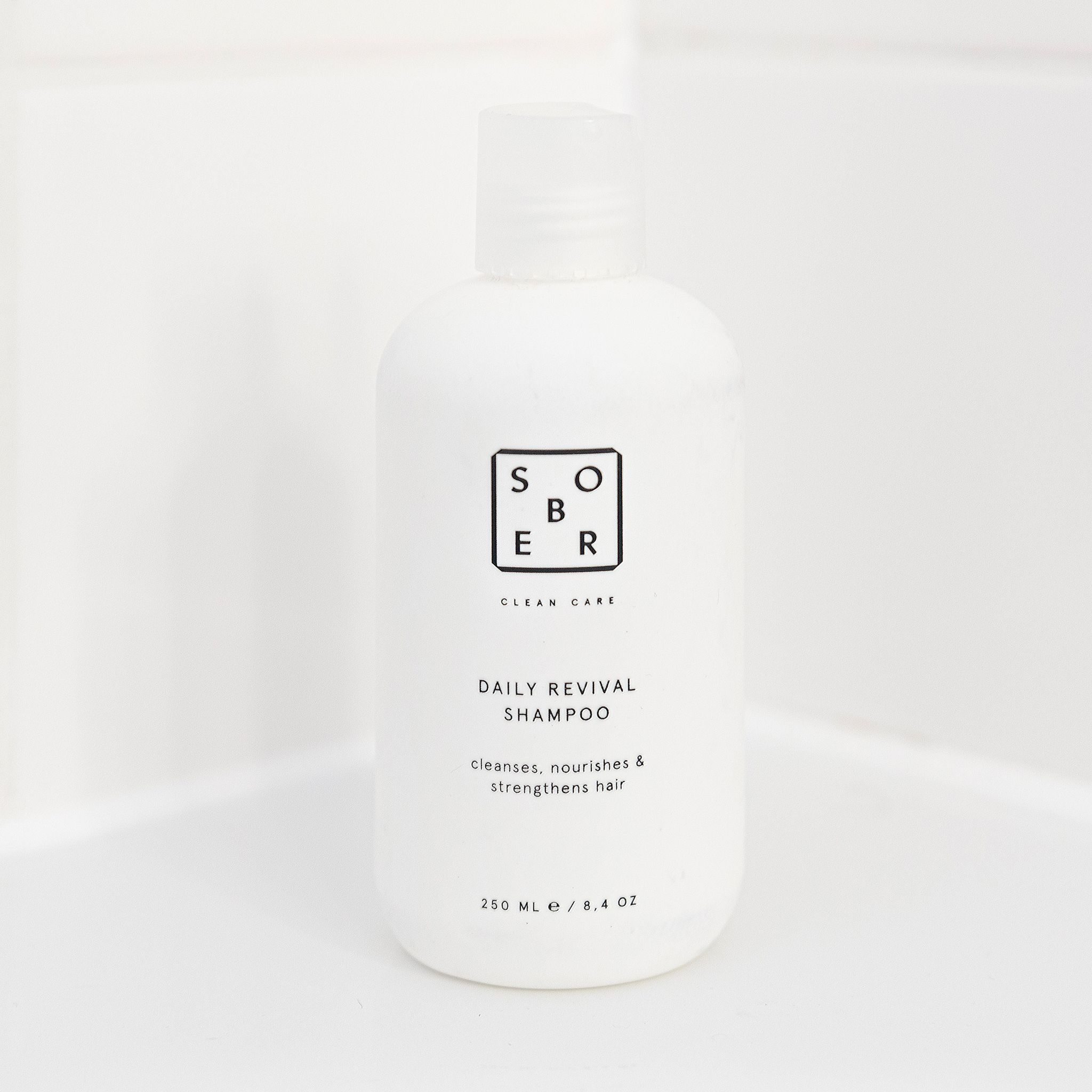Weiße Shampoo-Flasche mit schwarzem Text. Schriftzug: SOBER, DAILY REVIVAL SHAMPOO, 250 ml / 8.4 oz.