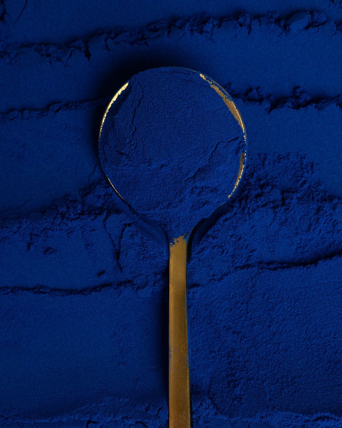 Ein Löffel mit blauem Pulver, aufgetragen auf eine Schicht aus Pulver.