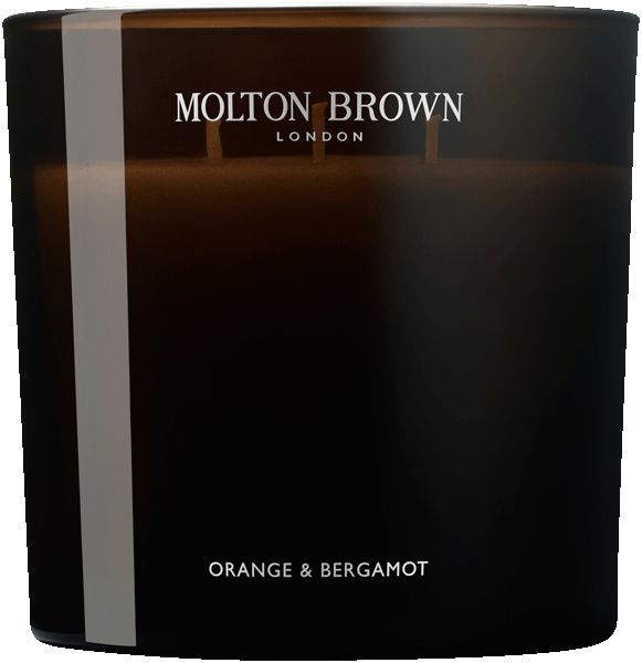 Nahaufnahme einer dunklen Glas-Duftkerze mit drei Dochten. Aufschrift: Molton Brown, Orange & Bergamot.