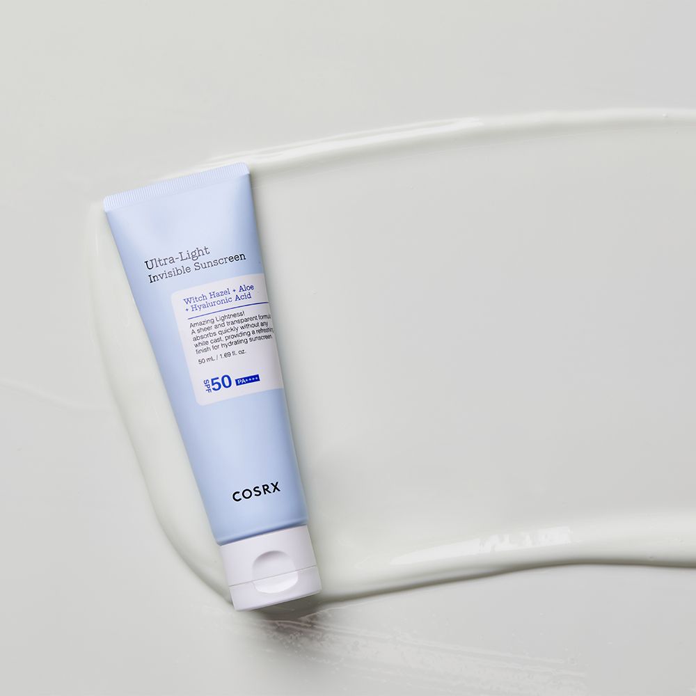 COSRX Ultra Light Invisible Sunscreen Tube auf einer weißen Creme-Oberfläche.