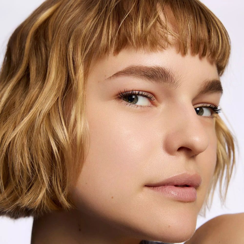 Porträt einer jungen Frau mit kurzem, blondem Haar und dezentem Make-up. Sie blickt direkt in die Kamera.