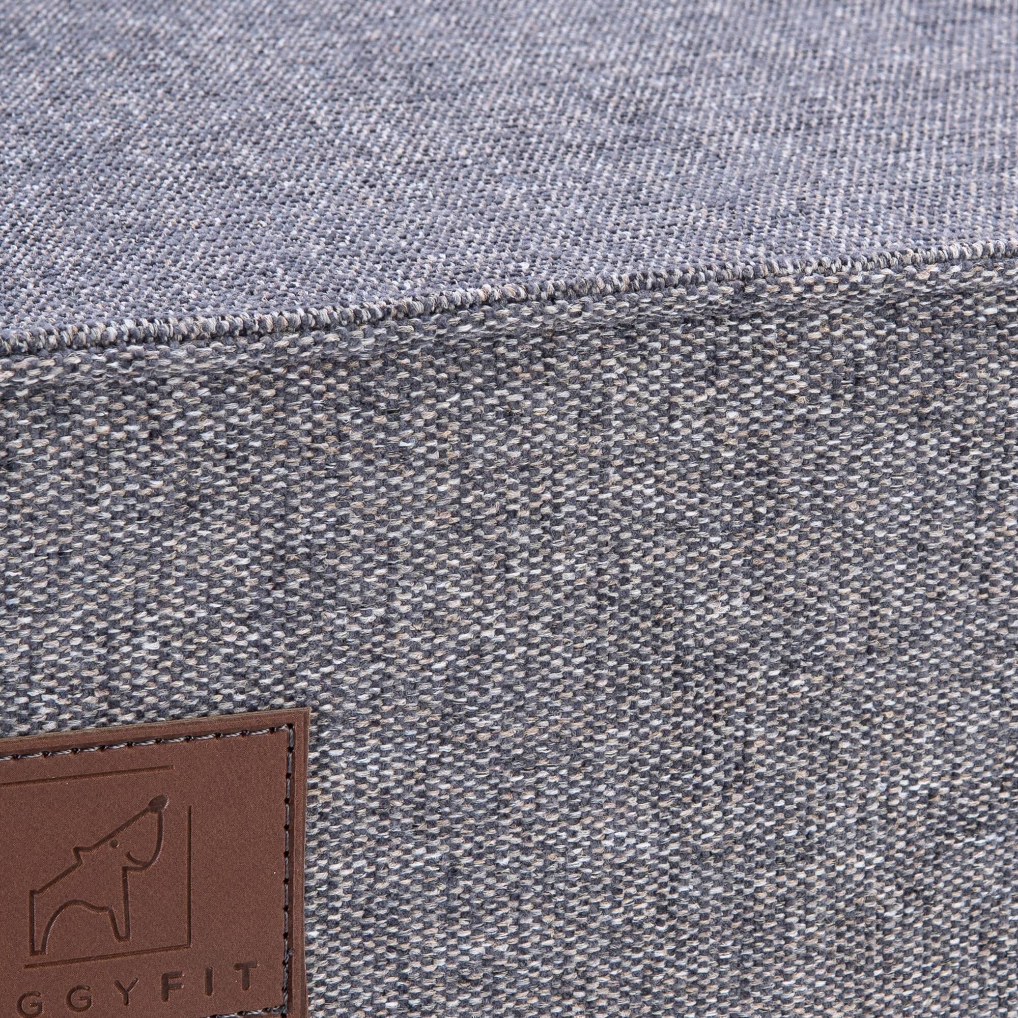 Nahaufnahme der grauen Hundematte. Braunes Label mit Logo. Text: GGYFIT.