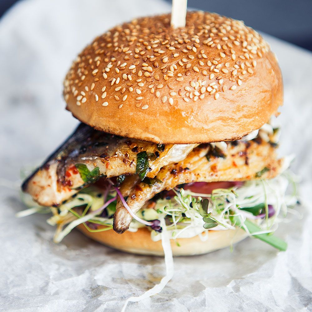 Fischburger mit Sesambrötchen, Salat und Spieß. Fischfilet gegrillt.