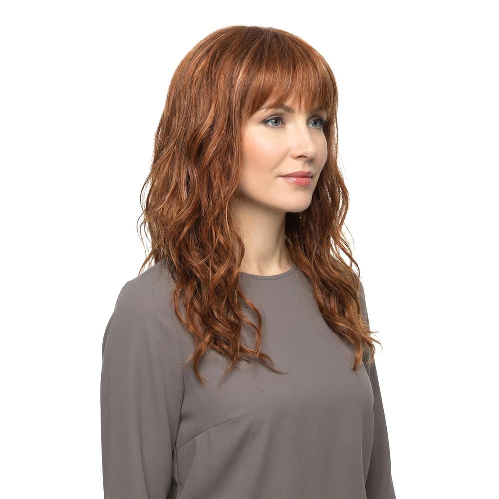 Perücke Kiky von trendhair. Rötlich-braune, gewellte Kunsthaarperücke mit Pony. Dreiviertelansicht einer Frau.