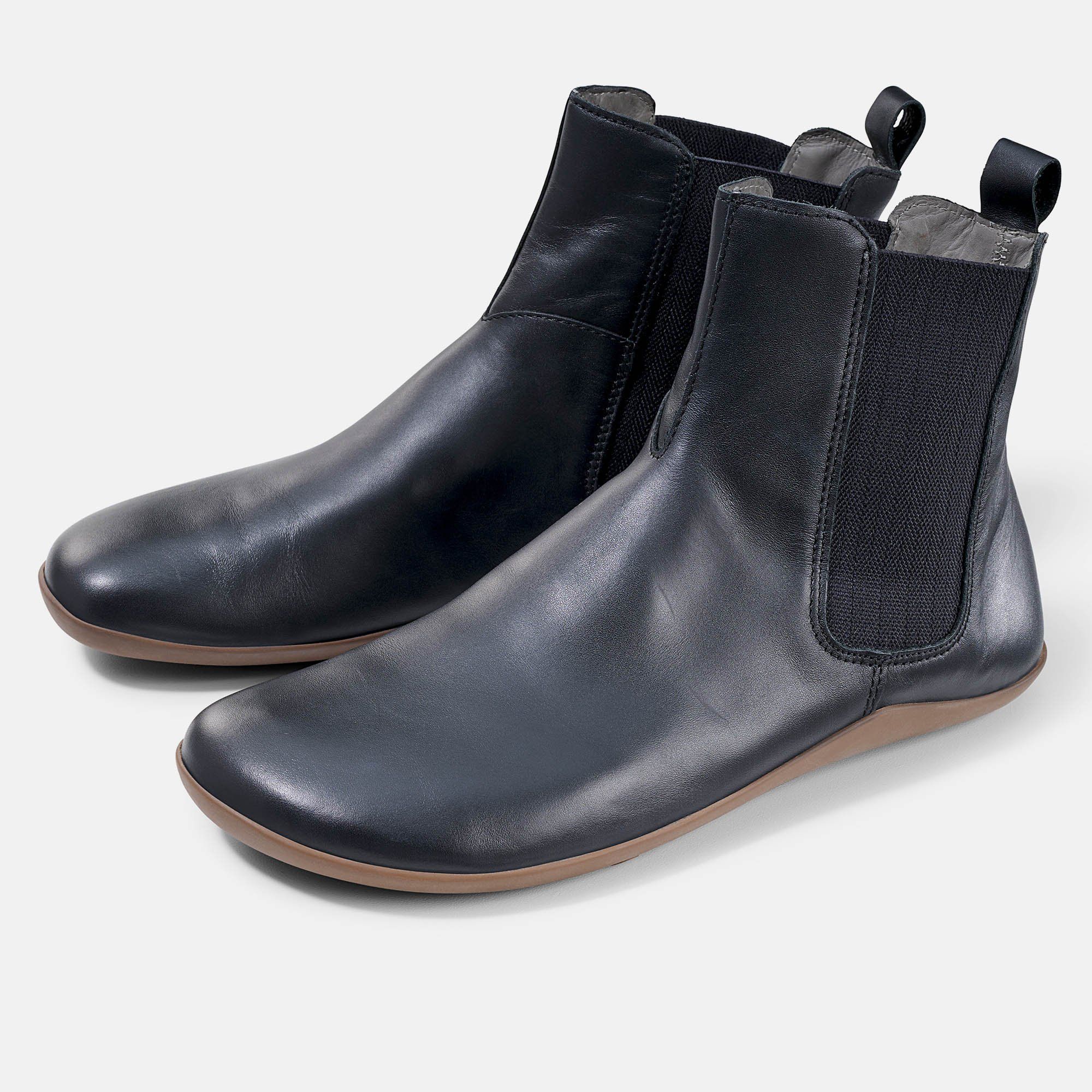 Schwarze Stiefeletten mit brauner Sohle. Elastischer Einsatz an der Seite. Zwei Schuhe nebeneinander.