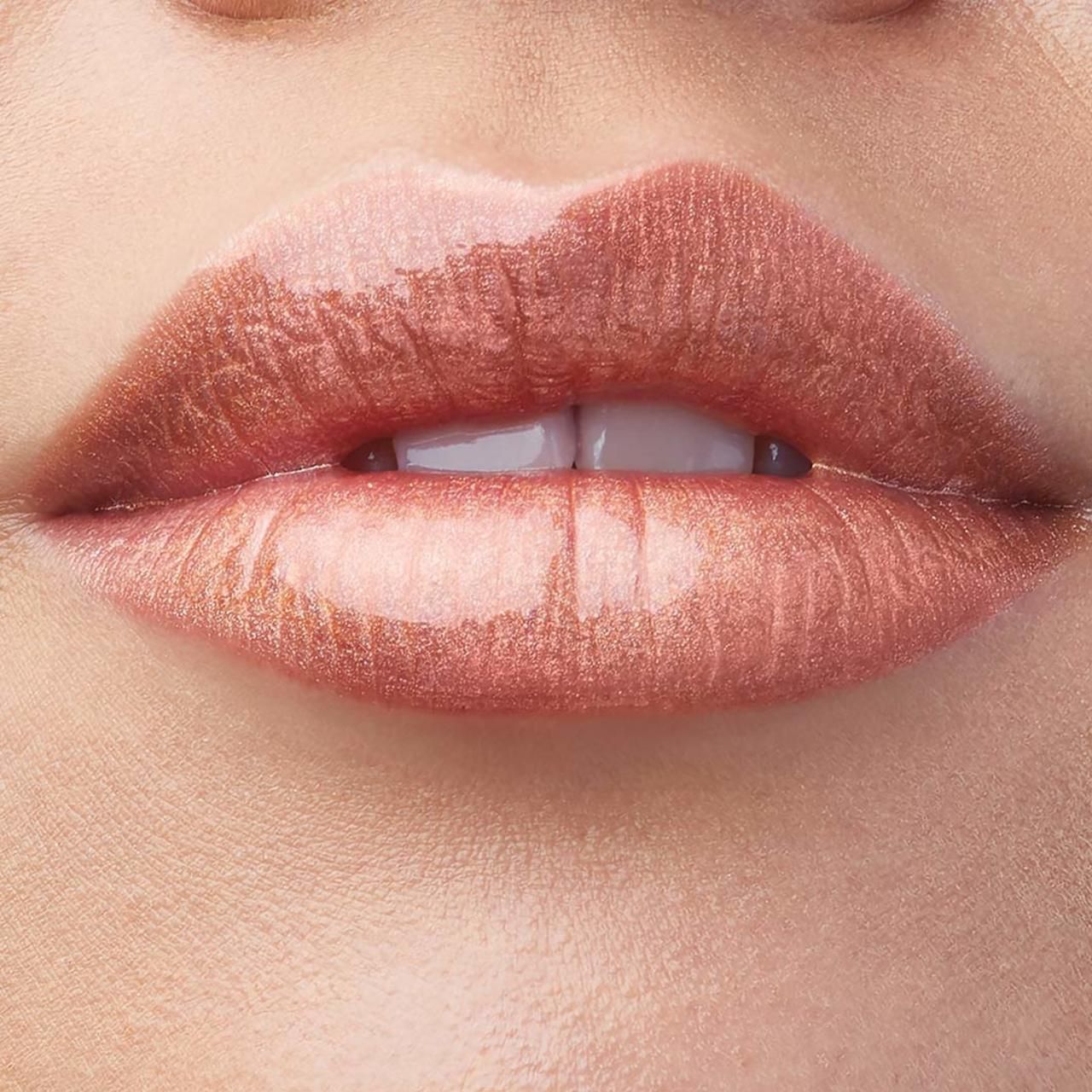 Nahaufnahme von Lippen mit glänzendem, goldfarbenem Lipgloss. Die Lippen sind leicht geöffnet, Zähne sichtbar.