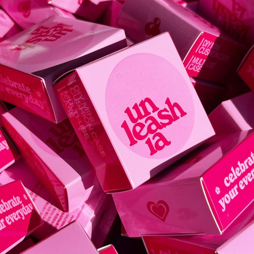 Mehrere rosa Kartons mit der Aufschrift 'unleash ia' und 'DIY Mini Cushion Case'.
