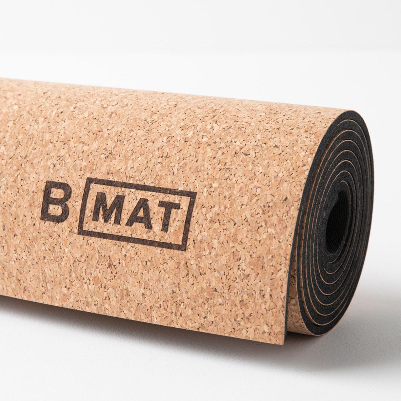 Gerollte Yogamatte aus Naturkork. Auf der Oberfläche ist der Schriftzug "B MAT" zu sehen.