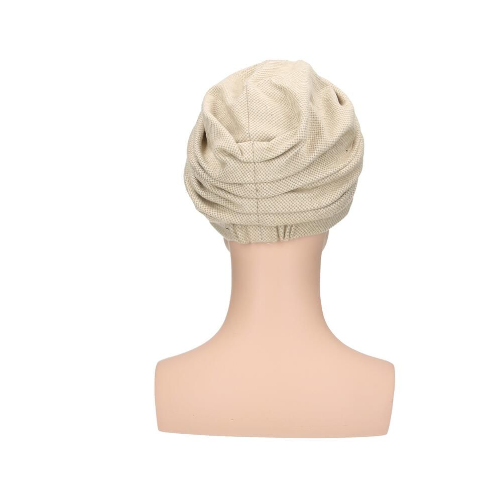 Rückansicht eines beigefarbenen Stoffturbans mit Knoten, auf einer Schaufensterpuppe.