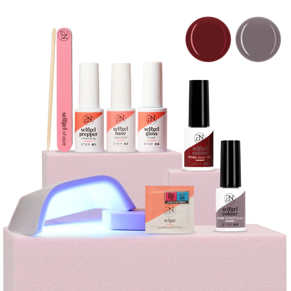Nagelpflege-Set mit UV-Lampe, Nagelfeile, Holzstab, Reinigungstücher und Nagellack in Rot und Taupe. PN-Logo sichtbar.