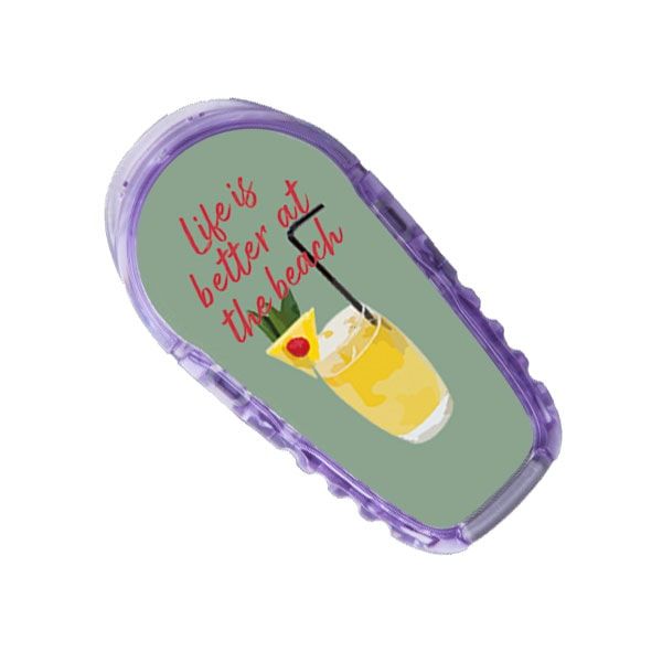 Aufkleber mit lila Rahmen und grünem Hintergrund. Text: Life is better at the beach. Bild eines Cocktails.