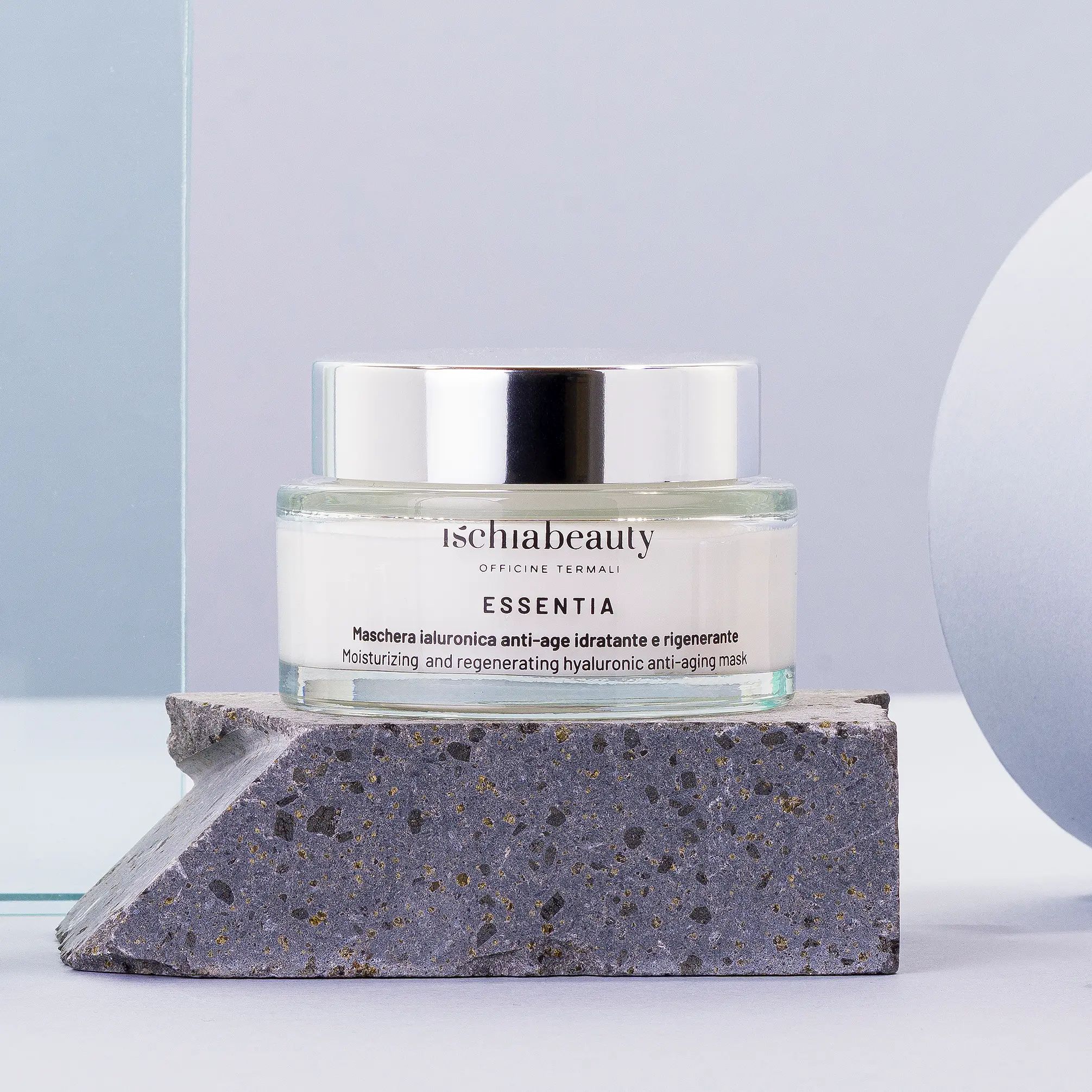 Glasbehälter mit Creme, silberner Deckel. Aufschrift: ischiabeauty ESSENTIA. Auf Stein.