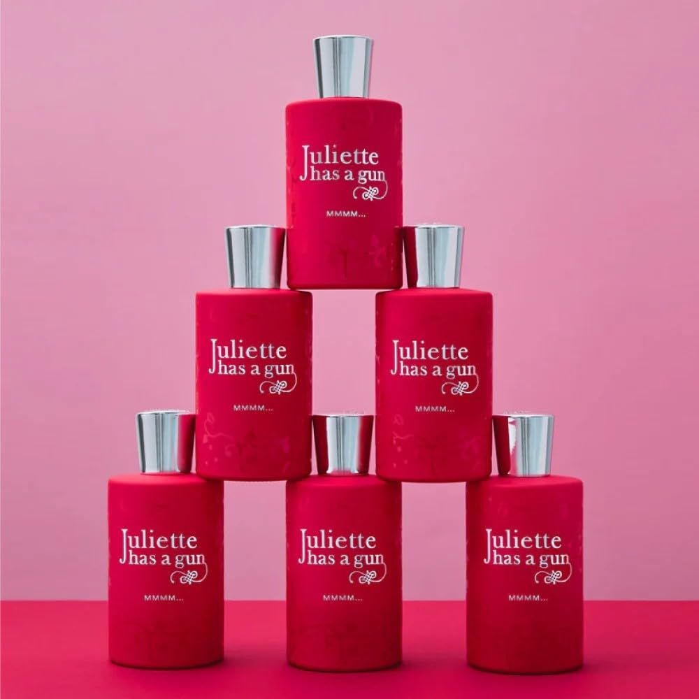Sieben rote Parfumflaschen mit silbernen Deckeln. Aufschrift: Juliette has a gun. MMMM... Eau de Parfum. Auf rosa Hintergrund.