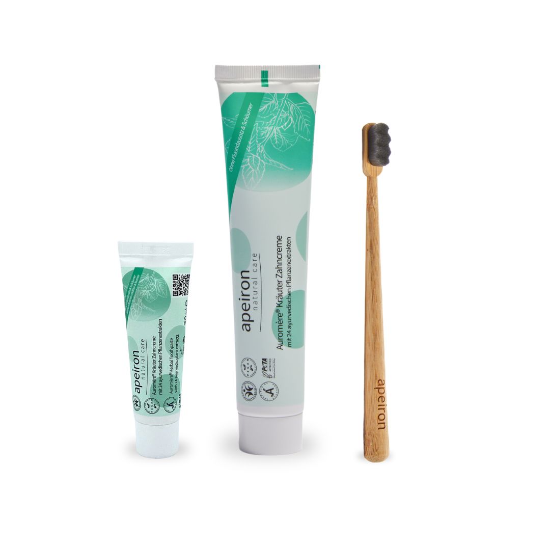 Zahncreme-Tuben, weiß-grün, und Zahnbürste aus Holz. Marke Apeiron.