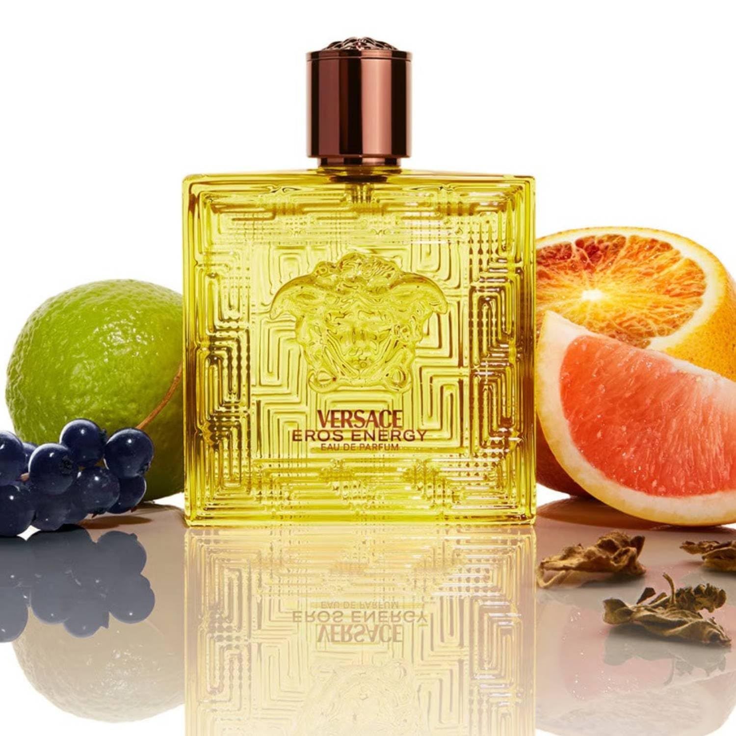 Versace Eros Energy EdP Flasche mit Früchten. Gelbe Flasche, quadratisch, Medusa-Logo. Früchte: Grapefruit, Limette, Trauben.