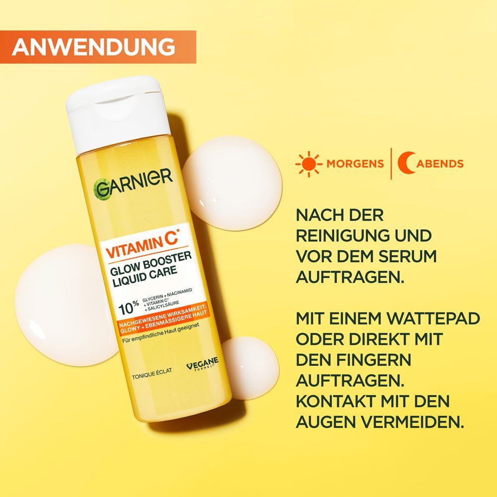 Garnier Vitamin C Glow Booster Liquid Care. Flasche und Tropfen auf gelbem Hintergrund. Text: Morgens, abends. Anwendungshinweise.