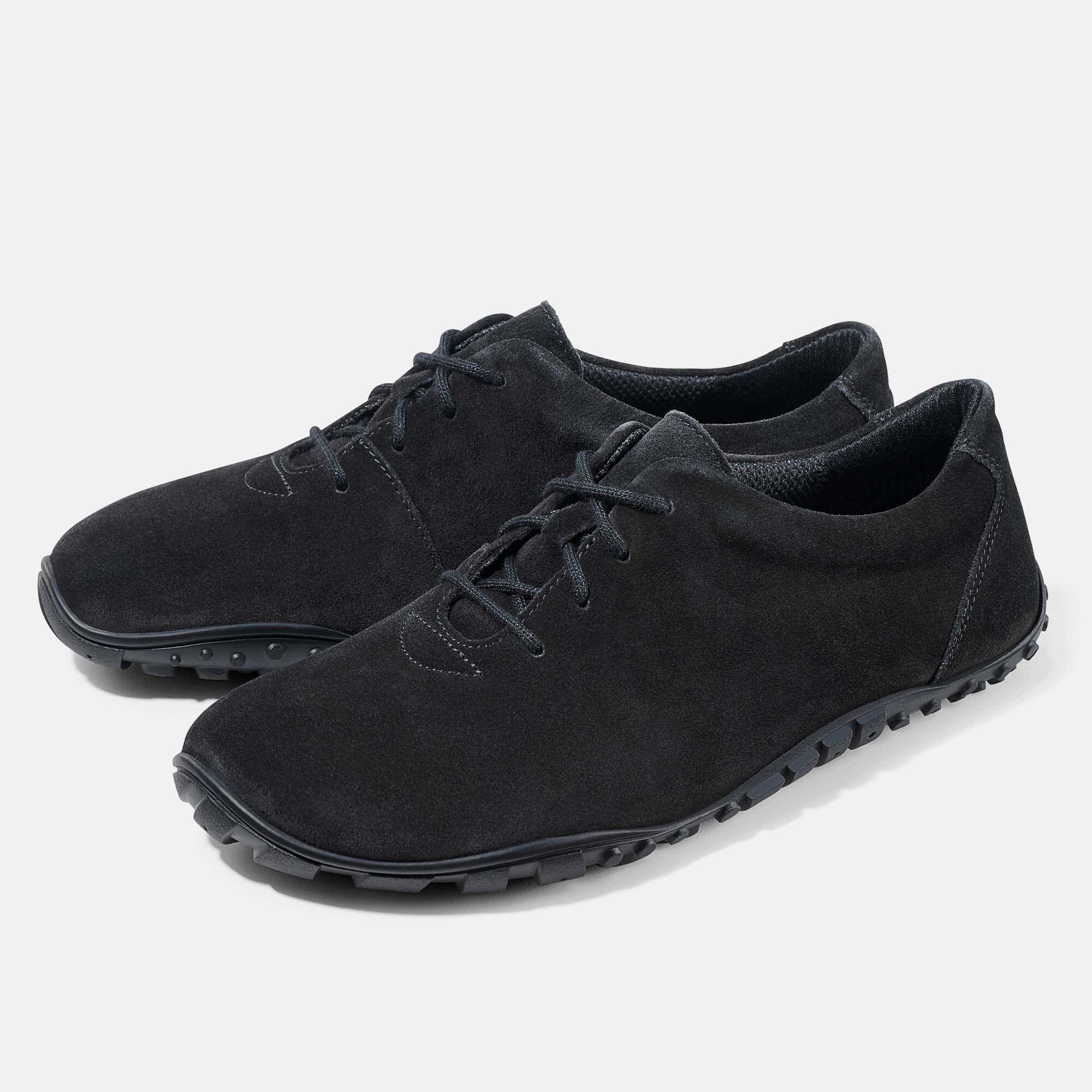 Zwei schwarze Wildlederschuhe mit Schnürung und profilierten Gummisohlen.