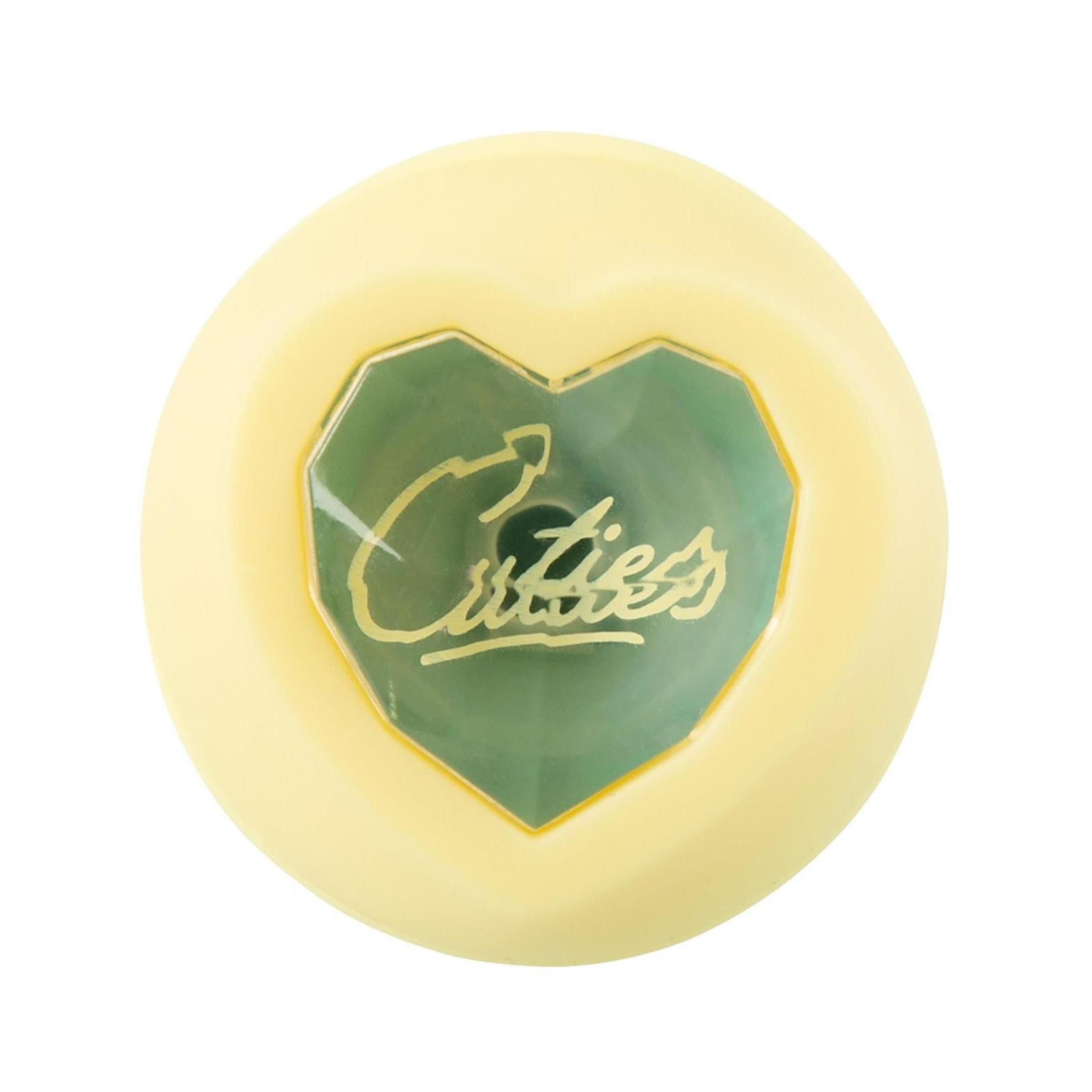 Gelber Mini-Vibrator, Herzform. Grüner Einsatz mit Cuties-Logo. Auf weißem Hintergrund.