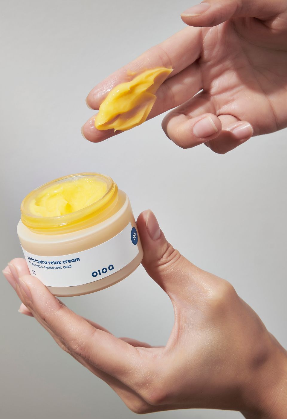 Hände halten Cremebehälter und Creme. Aufschrift: "pufa hydra relax cream" und "oioa".