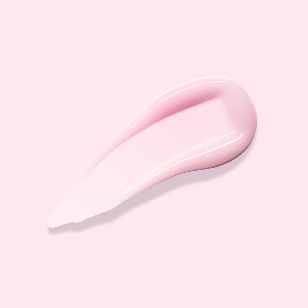 Una goccia di crema corpo rosa su sfondo rosa. La crema ha una consistenza liscia e lucida ed è applicata con un motivo a goccia.