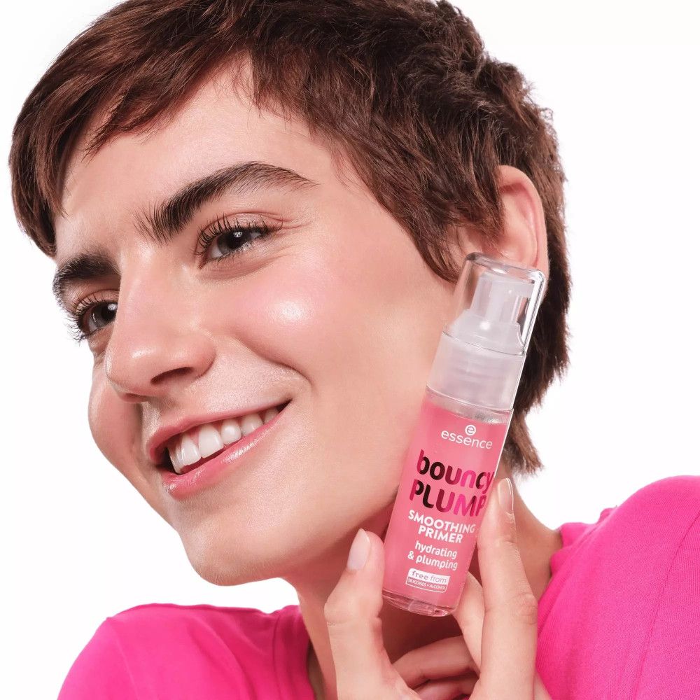 Frau hält eine rosa Foundation-Primer-Flasche. Auf der Flasche steht Bouncy Plump, Smoothing Primer.