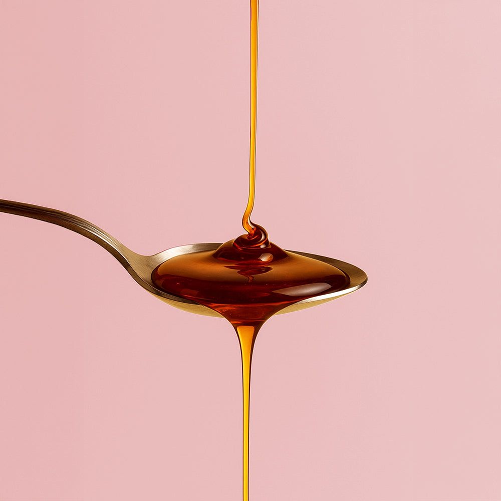 Flüssigkeit wird aus einem Löffel gegossen. Rosa Hintergrund.