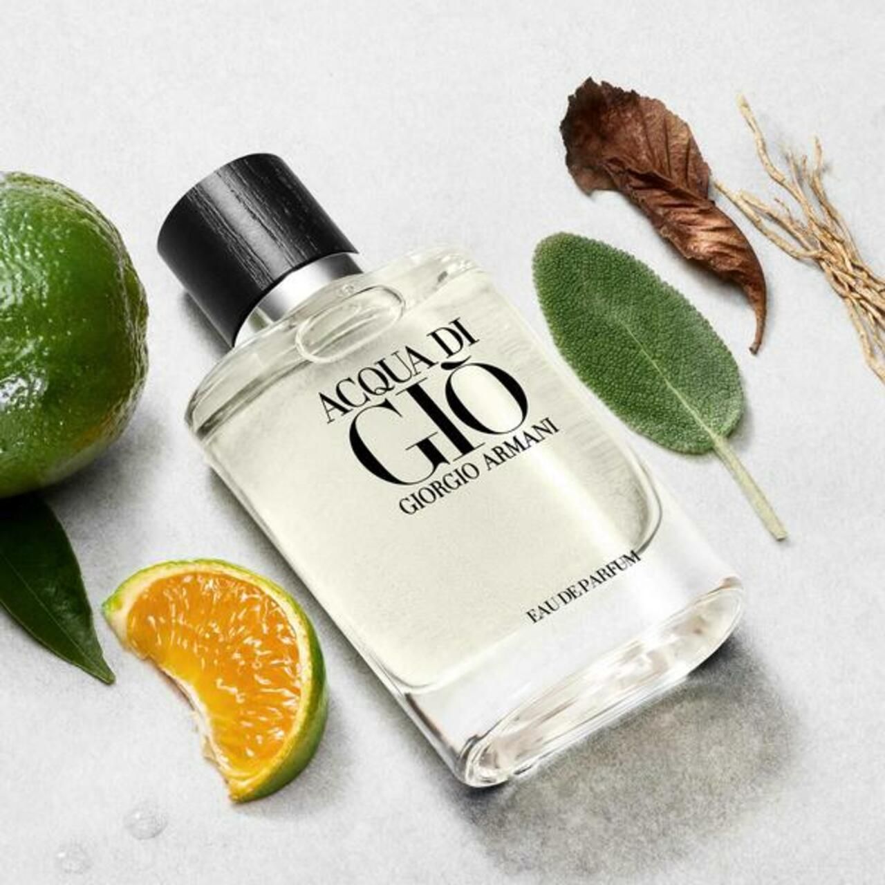 Glasflakon mit schwarzem Verschluss. Aufschrift: Acqua di Giò, Eau de Parfum, Giorgio Armani. Mit Limette, Orange, Blättern.
