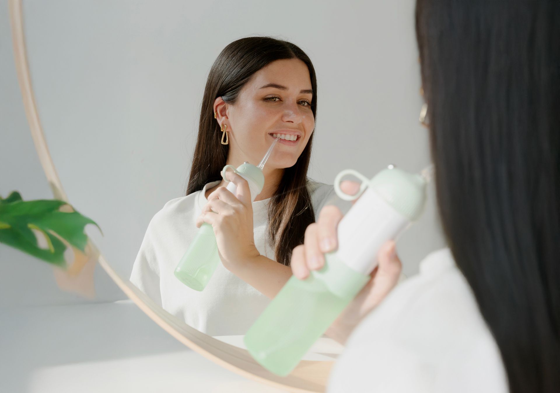 Frau im Spiegel mit Wasserflosser. Grüner Wasserflosser. Goldene Ohrringe. Lächelt.