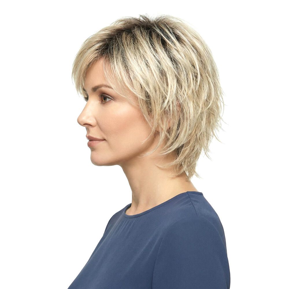 Blond gefärbte Perücke mit kurzem, gestuftem Schnitt. Seitenansicht einer Frau mit blauem Oberteil.