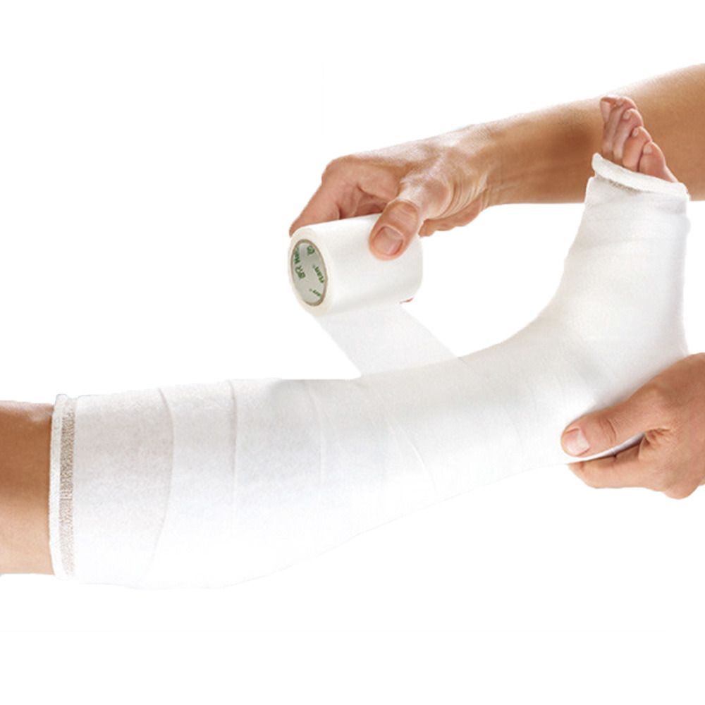 Fußverband mit weißem Verbandmaterial. Eine Hand wickelt den Verband um den Fuß, die andere hält den Fuß.