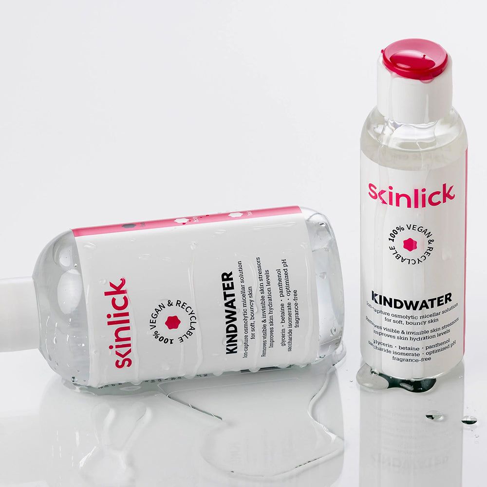 Zwei Flaschen SKINLICK Kindwater Mizellenwasser, eine liegend. Transparente Flüssigkeit.