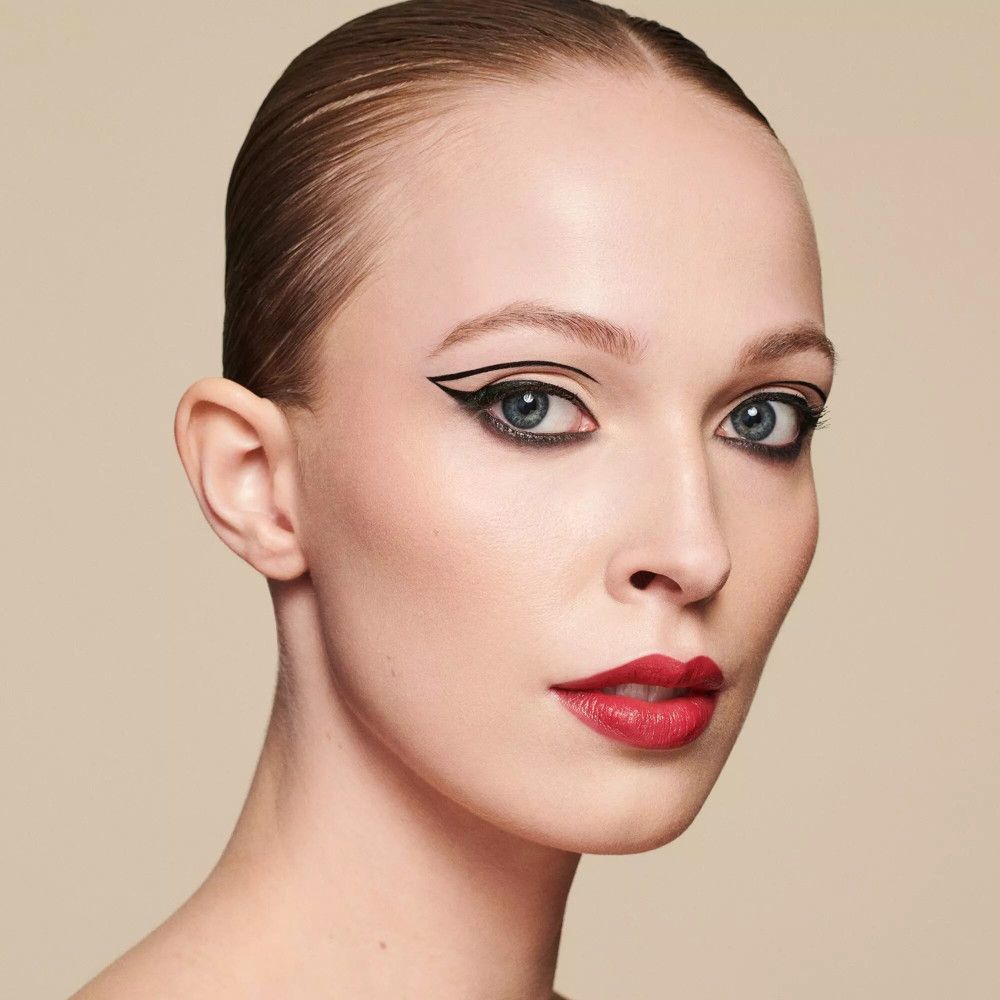 Porträt einer Frau mit rotem Lippenstift und Eyeliner. Hintergrund: hell.