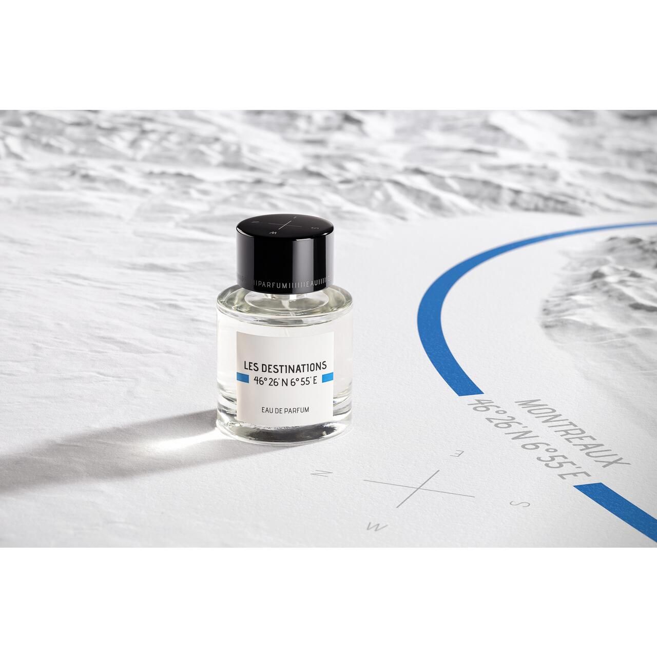 Glasflakon mit schwarzem Deckel auf einer Karte. Aufschrift: Les Destinations, 46°26'N 6°55'E, Eau de Parfum. Karte mit blauer Linie.