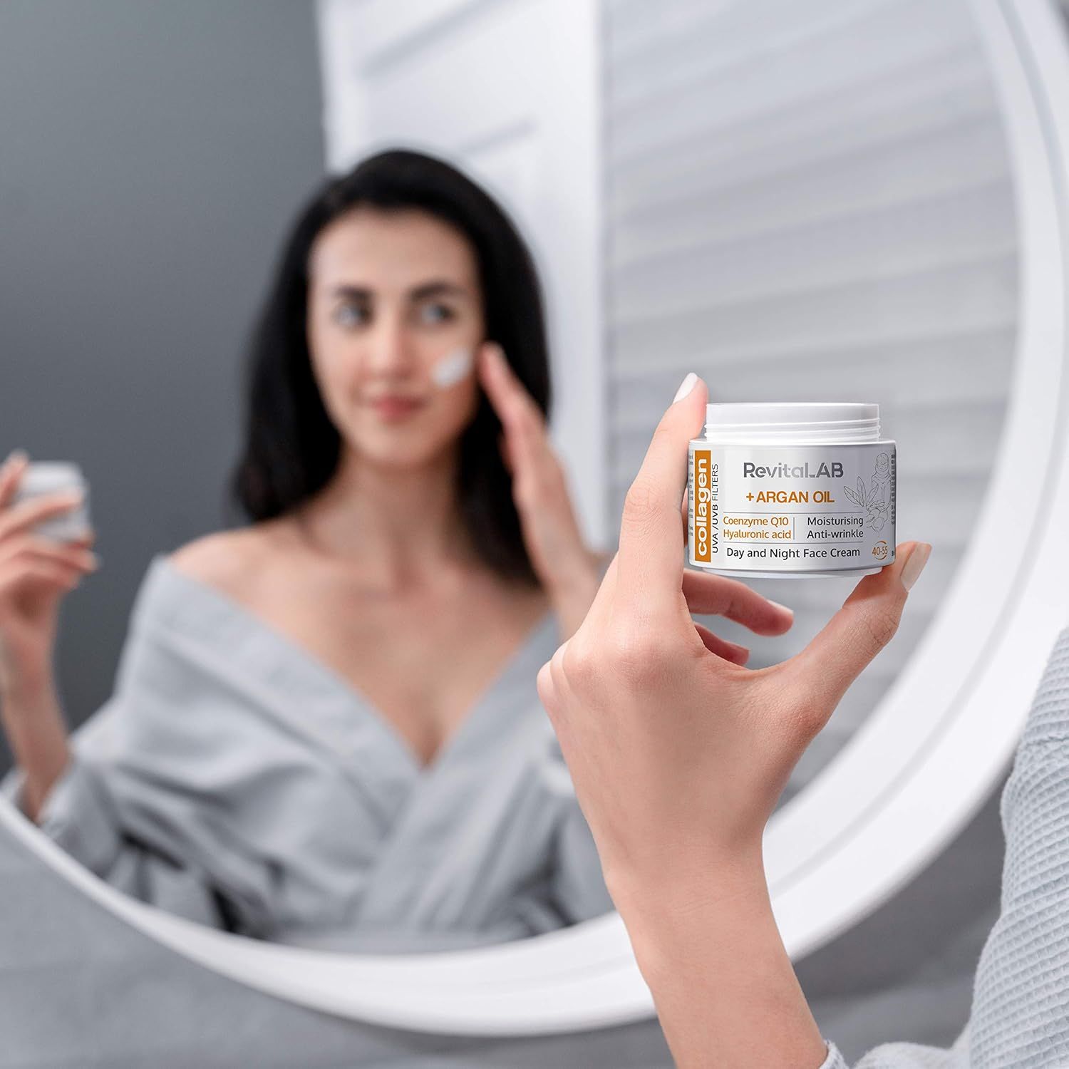 Frau im Spiegel hält einen Creme-Tiegel. Aufschrift: RevitaLAB + ARGAN OIL, Collagen, UVA/UVB Filters, Coenzyme Q10, Hyaluronic acid, Day and Night Face Cream.