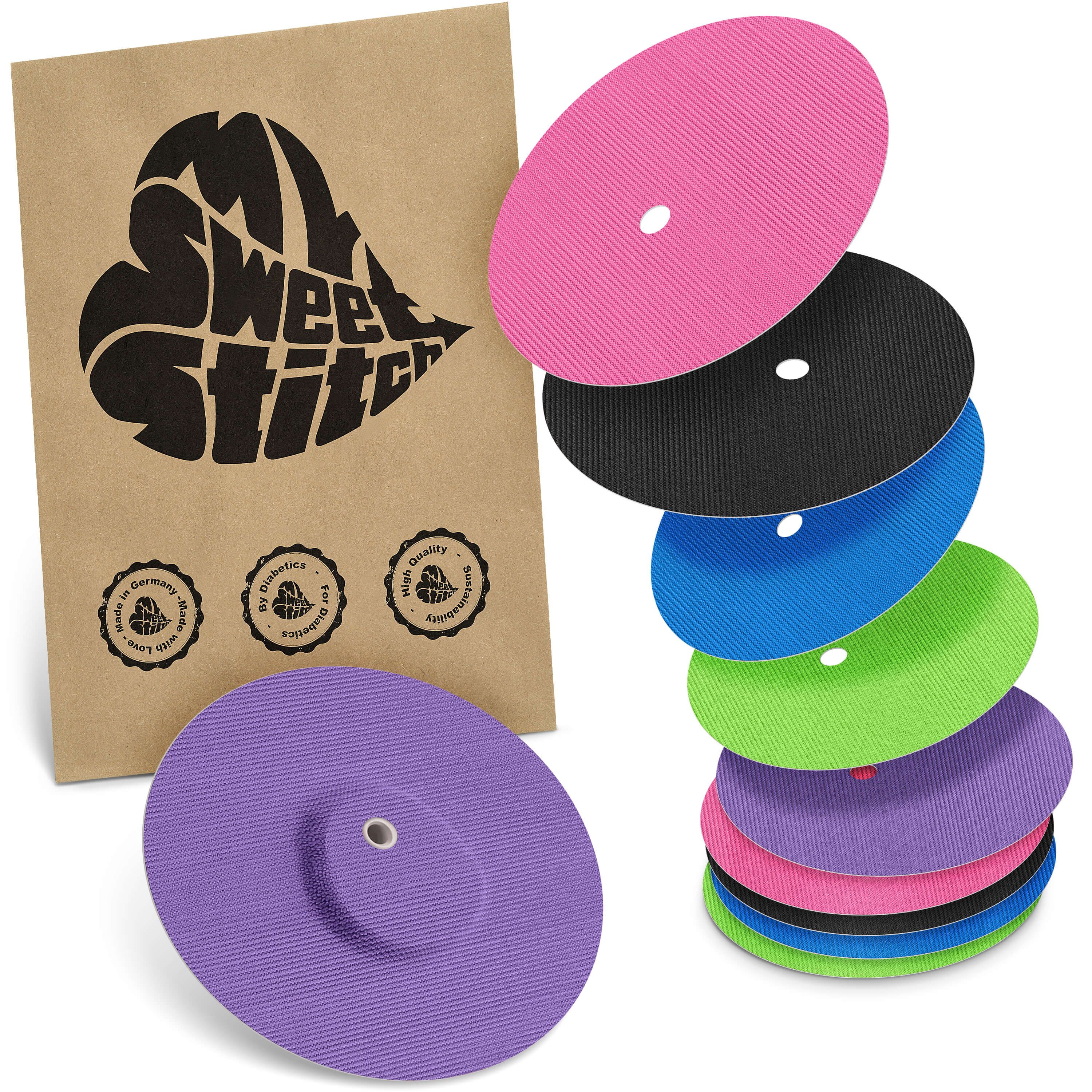 Mehrfarbige Fixierpflaster, teilweise gestapelt. Braune Verpackung mit Logo und Qualitätssiegeln.