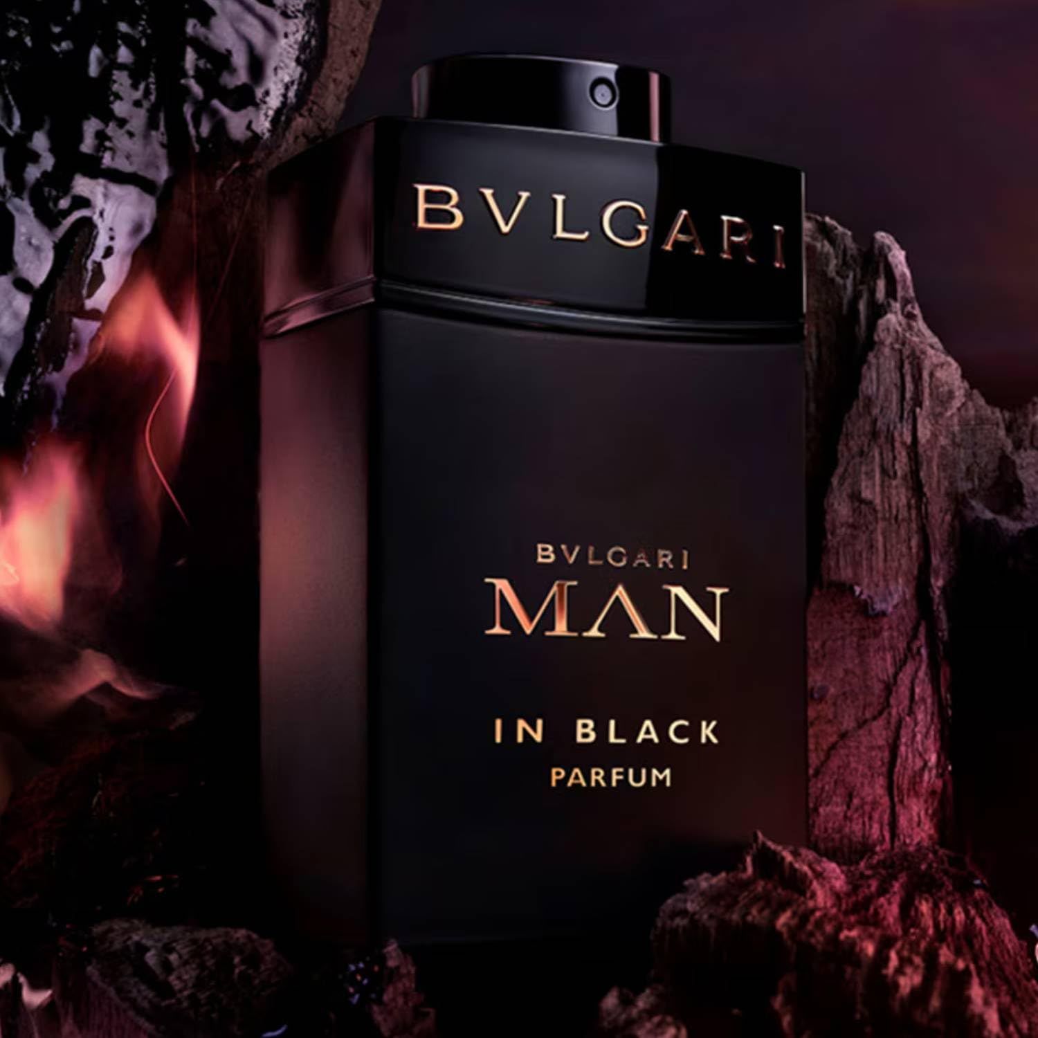 Schwarzer Flakon Bvlgari Man In Black Parfum vor einem unscharfen Hintergrund mit Felsen und Flammen.