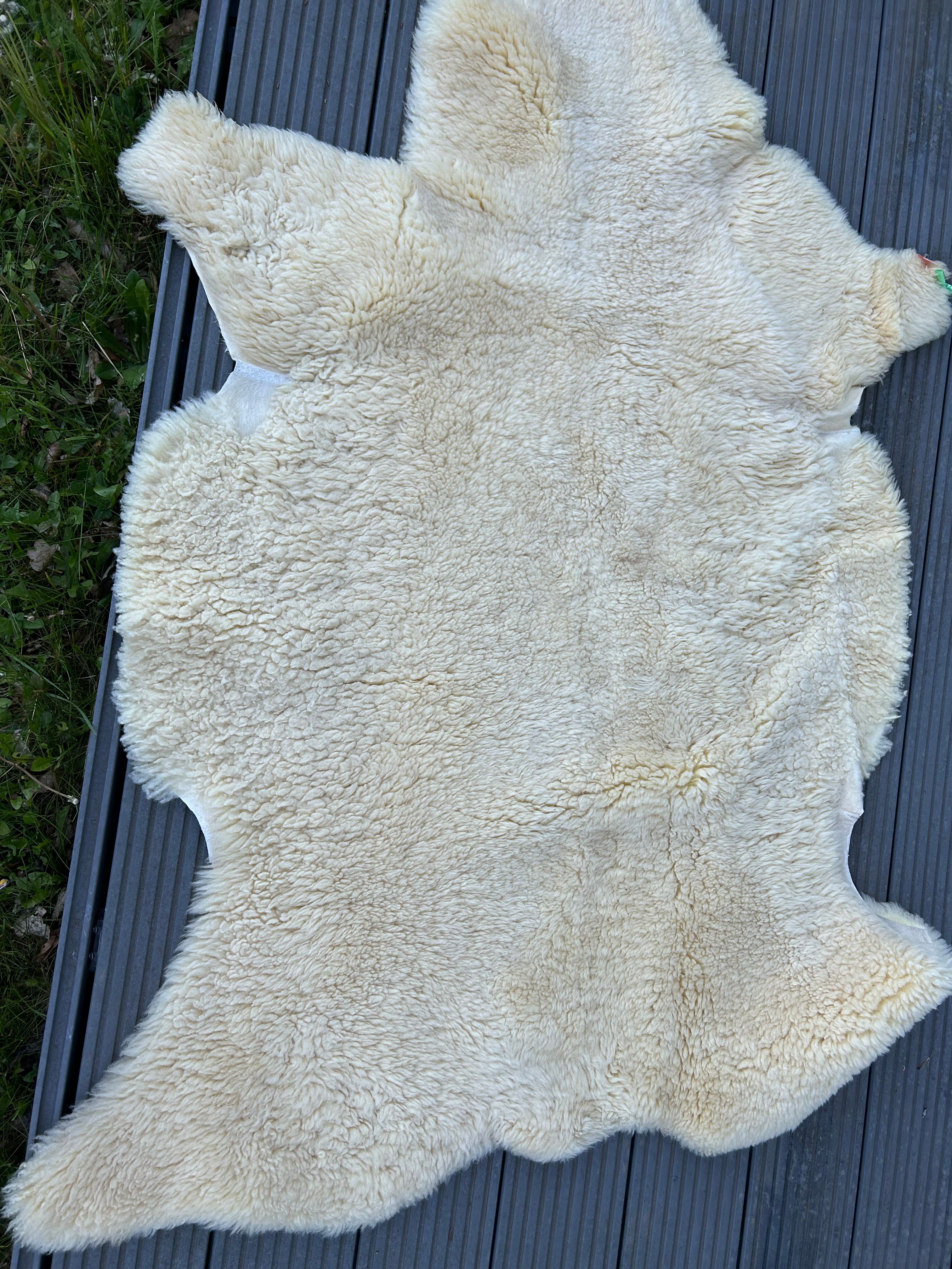 Gelbes Lammfell auf einer Holzoberfläche. Die Form ist unregelmäßig.