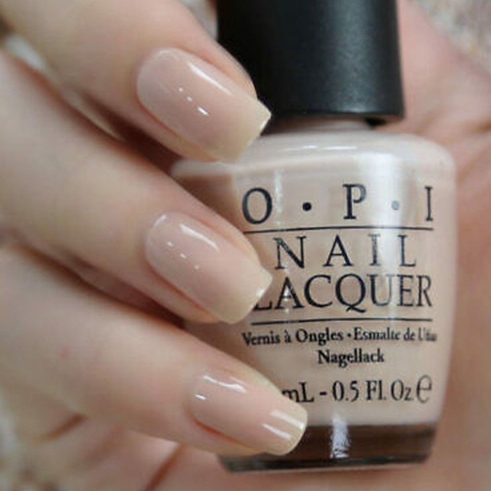 Hand mit lackierten Nägeln. Nagellackflasche mit OPI-Logo. Beige Nagellackfarbe. Produktbezeichnung und Volumenangabe.